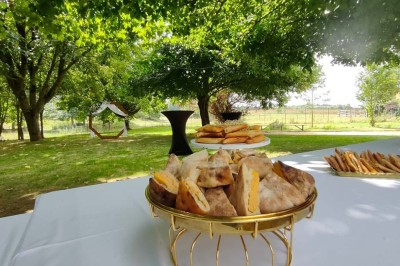 Voiture ancienne blanche décorée de fleurs, stationnée devant un bâtiment en pierre avec un toit en ardoise.