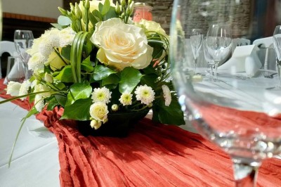 Voiture ancienne blanche décorée de fleurs, stationnée devant un bâtiment en pierre avec un toit en ardoise.