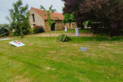 Voiture ancienne blanche décorée de fleurs, stationnée devant un bâtiment en pierre avec un toit en ardoise.
