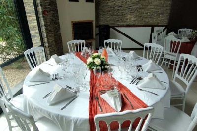 Voiture ancienne blanche décorée de fleurs, stationnée devant un bâtiment en pierre avec un toit en ardoise.