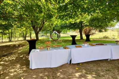 Voiture ancienne blanche décorée de fleurs, stationnée devant un bâtiment en pierre avec un toit en ardoise.