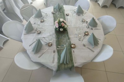 Voiture ancienne blanche décorée de fleurs, stationnée devant un bâtiment en pierre avec un toit en ardoise.