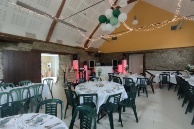 Voiture ancienne blanche décorée de fleurs, stationnée devant un bâtiment en pierre avec un toit en ardoise.