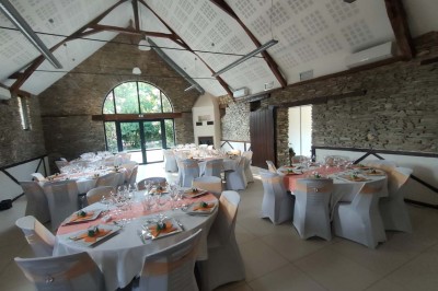 Voiture ancienne blanche décorée de fleurs, stationnée devant un bâtiment en pierre avec un toit en ardoise.