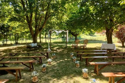 Voiture ancienne blanche décorée de fleurs, stationnée devant un bâtiment en pierre avec un toit en ardoise.