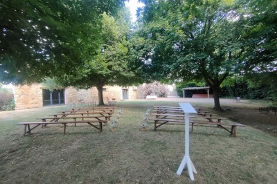 Voiture ancienne blanche décorée de fleurs, stationnée devant un bâtiment en pierre avec un toit en ardoise.