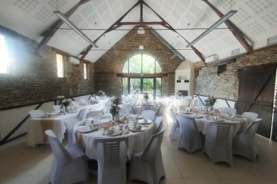 Voiture ancienne blanche décorée de fleurs, stationnée devant un bâtiment en pierre avec un toit en ardoise.