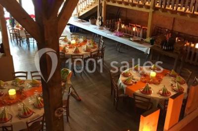 Bâtiments en bois avec une chapelle, une roulotte et des bottes de foin, entourés de verdure.