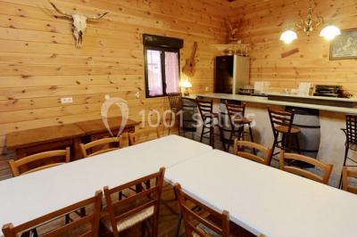 Bâtiments en bois avec une chapelle, une roulotte et des bottes de foin, entourés de verdure.