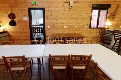 Bâtiments en bois avec une chapelle, une roulotte et des bottes de foin, entourés de verdure.