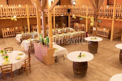 Bâtiments en bois avec une chapelle, une roulotte et des bottes de foin, entourés de verdure.