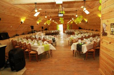 Bâtiments en bois avec une chapelle, une roulotte et des bottes de foin, entourés de verdure.