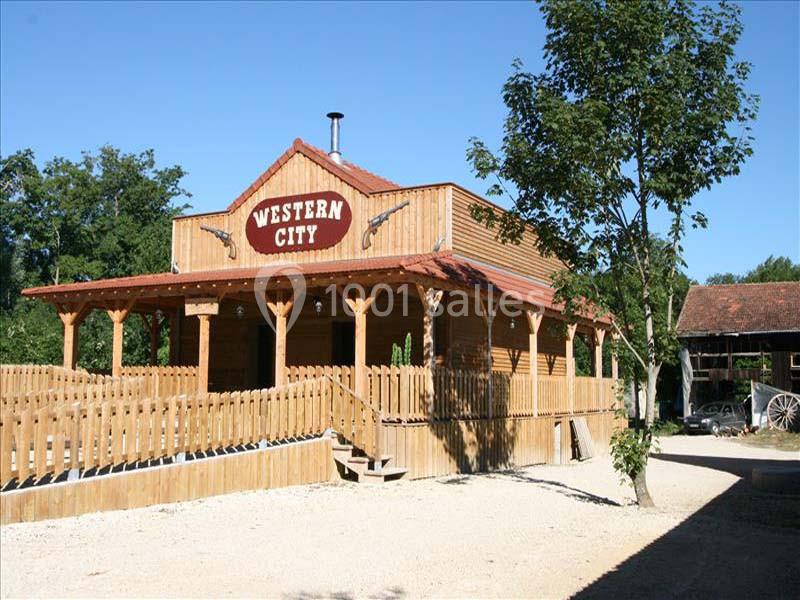 Bâtiment en bois de style western avec une enseigne ’Western City’, entouré d'une clôture et d'arbres.