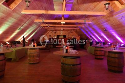 Bâtiments en bois avec une chapelle, une roulotte et des bottes de foin, entourés de verdure.