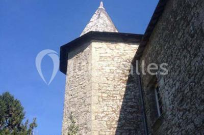 Vue d'un paysage boisé avec un bâtiment en pierre et un toit en ardoise partiellement visible au premier plan.