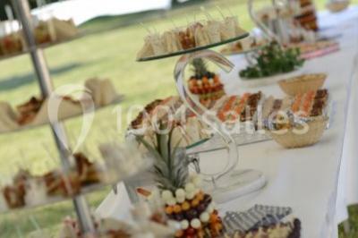 Mobilier en palettes décoré de tissu blanc et de fleurs roses, disposé dans un jardin ombragé.