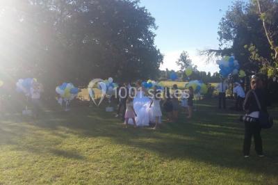 Mobilier en palettes décoré de tissu blanc et de fleurs roses, disposé dans un jardin ombragé.