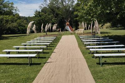 Mobilier en palettes décoré de tissu blanc et de fleurs roses, disposé dans un jardin ombragé.