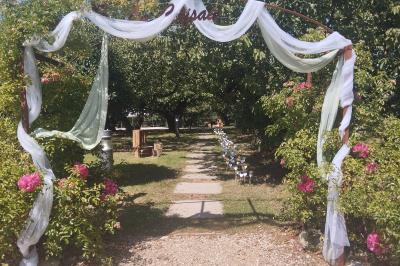 Mobilier en palettes décoré de tissu blanc et de fleurs roses, disposé dans un jardin ombragé.