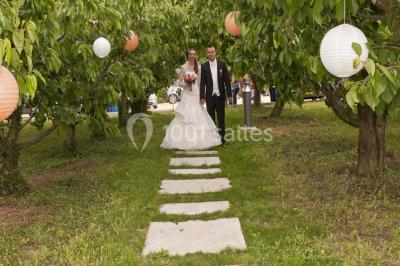 Mobilier en palettes décoré de tissu blanc et de fleurs roses, disposé dans un jardin ombragé.