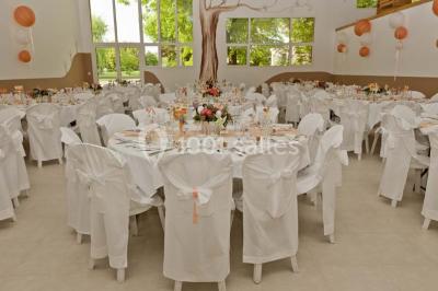 Mobilier en palettes décoré de tissu blanc et de fleurs roses, disposé dans un jardin ombragé.