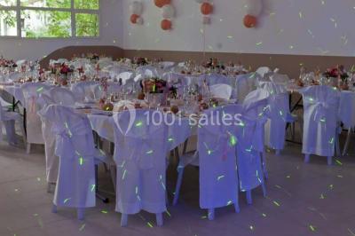 Mobilier en palettes décoré de tissu blanc et de fleurs roses, disposé dans un jardin ombragé.