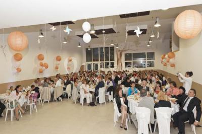 Mobilier en palettes décoré de tissu blanc et de fleurs roses, disposé dans un jardin ombragé.