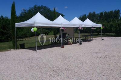 Mobilier en palettes décoré de tissu blanc et de fleurs roses, disposé dans un jardin ombragé.