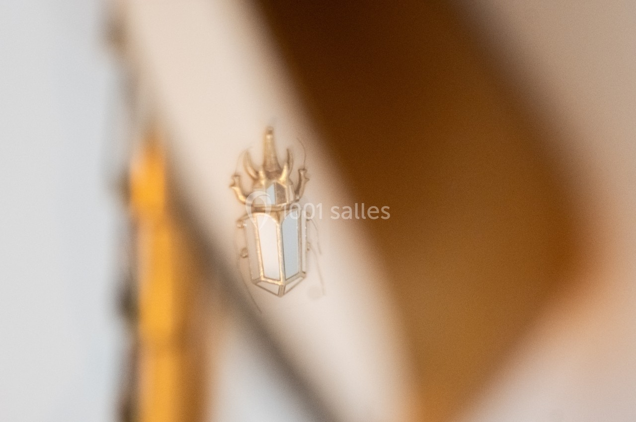 Reflet flou d'un blason doré et blanc sur une surface brillante, avec un arrière-plan beige.