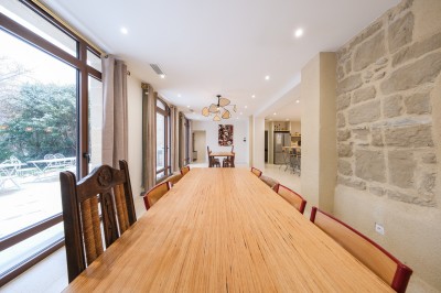 Salle décorée pour un événement, avec tables dressées, nappes noires, centres de table à plumes blanches et ballons dorés.