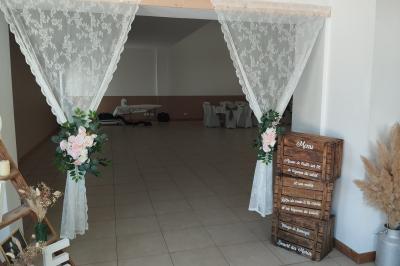 Salle décorée pour un événement, avec tables dressées, nappes noires, centres de table à plumes blanches et ballons dorés.