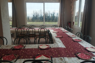 Salle décorée pour un événement, avec tables dressées, nappes noires, centres de table à plumes blanches et ballons dorés.