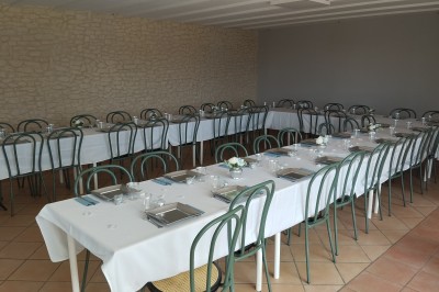 Salle décorée pour un événement, avec tables dressées, nappes noires, centres de table à plumes blanches et ballons dorés.