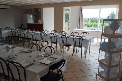 Salle décorée pour un événement, avec tables dressées, nappes noires, centres de table à plumes blanches et ballons dorés.
