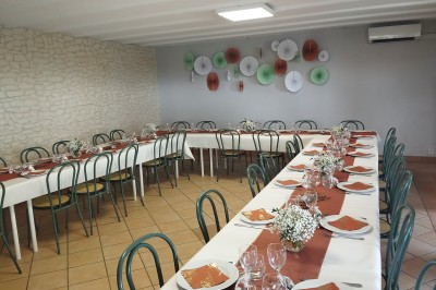 Salle décorée pour un événement, avec tables dressées, nappes noires, centres de table à plumes blanches et ballons dorés.