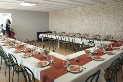 Salle décorée pour un événement, avec tables dressées, nappes noires, centres de table à plumes blanches et ballons dorés.