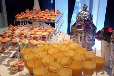 Table garnie de verrines, jus d'orange, pâtisseries et une lanterne décorative dans un cadre lumineux.