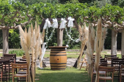 Trois bouteilles de vin posées sur un sol herbeux, entourées de fleurs blanches et jaunes.