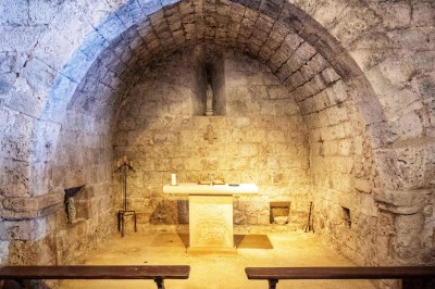 Trois bouteilles de vin posées sur un sol herbeux, entourées de fleurs blanches et jaunes.