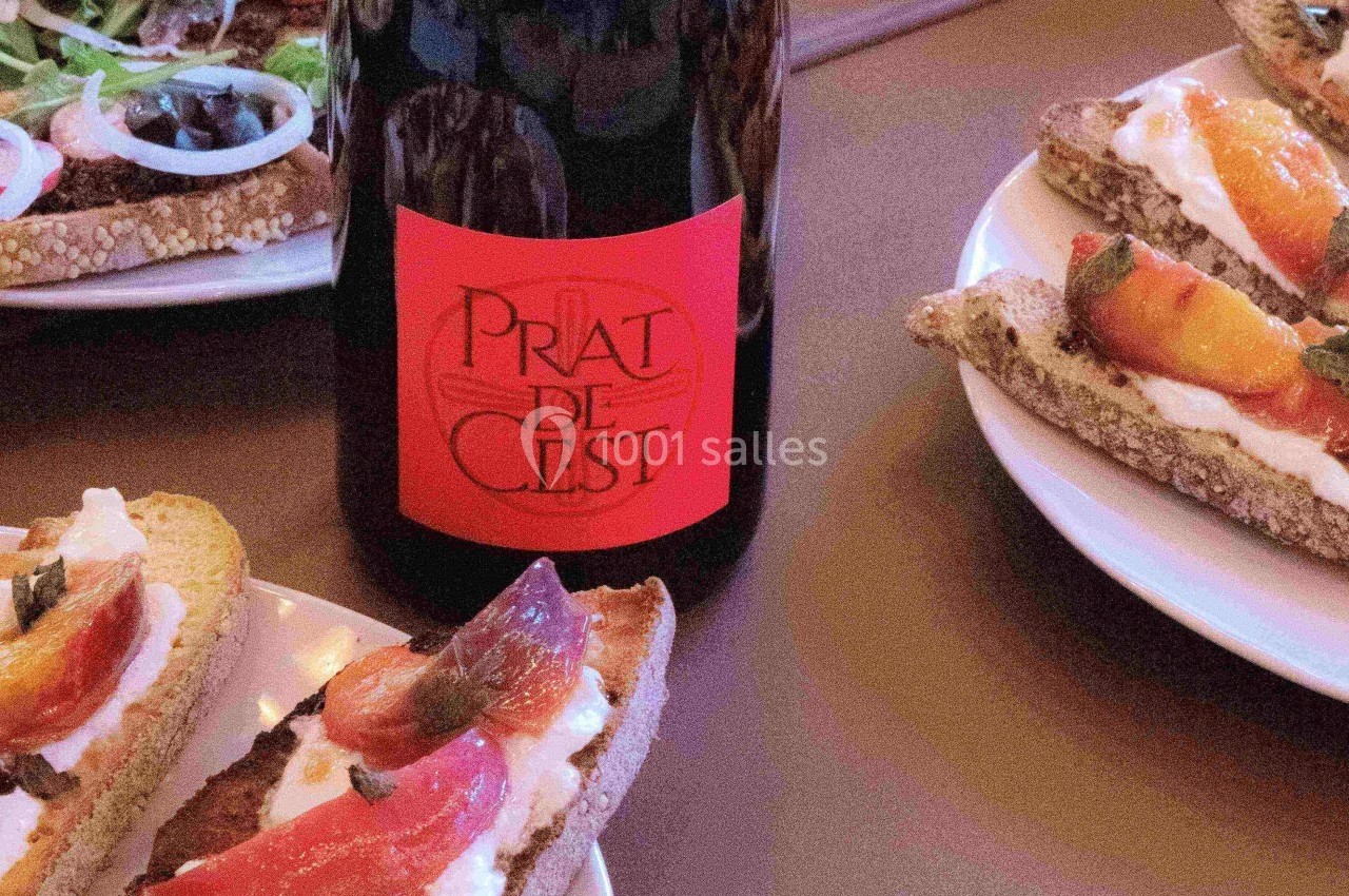 Bouteille de vin rouge avec étiquette rouge entourée d'assiettes de tartines garnies de fromage et de légumes.