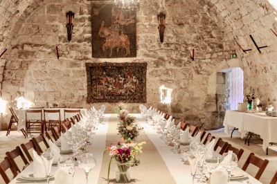Trois bouteilles de vin posées sur un sol herbeux, entourées de fleurs blanches et jaunes.