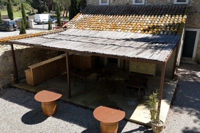 Trois bouteilles de vin posées sur un sol herbeux, entourées de fleurs blanches et jaunes.