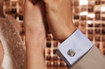 Trois bouteilles de vin posées sur un sol herbeux, entourées de fleurs blanches et jaunes.