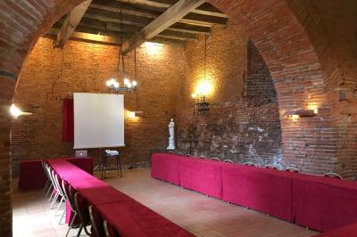 Un conférencier s'adresse à un public assis dans une salle avec un écran de projection et des murs en briques.
