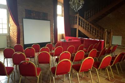 Un conférencier s'adresse à un public assis dans une salle avec un écran de projection et des murs en briques.