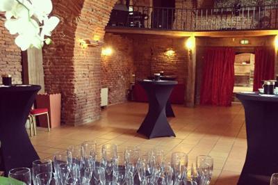 Un conférencier s'adresse à un public assis dans une salle avec un écran de projection et des murs en briques.