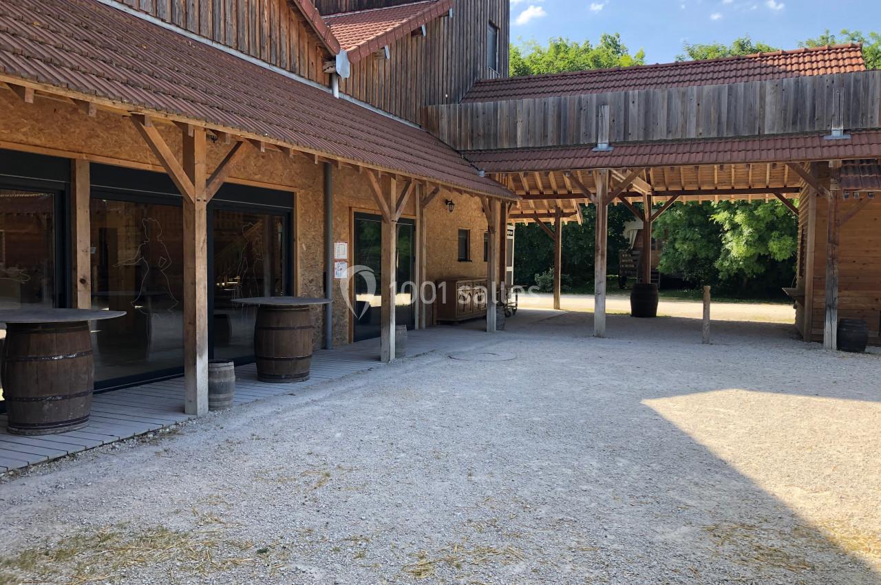 Cour intérieure d'un bâtiment en bois avec des toits en tuiles, des tonneaux et un sol en gravier.