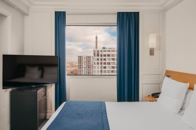 Vue de Paris à travers une fenêtre, montrant la Seine, un bâtiment moderne et l'horizon urbain avec des gratte-ciels.