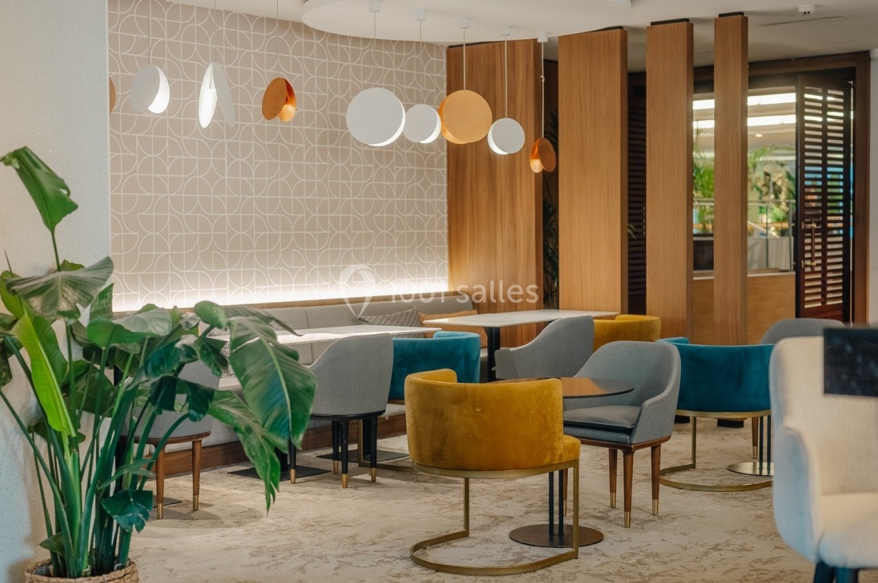 Salle moderne avec mobilier coloré, plantes décoratives et éclairage design, ambiance chaleureuse et épurée.