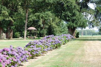 Vue aérienne d'une campagne avec des champs, des arbres, des maisons et des routes annotées pour indiquer des directions.